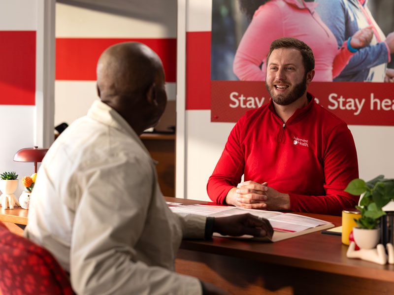 Independent Health RedShirt sitting at a desk meeting with a member